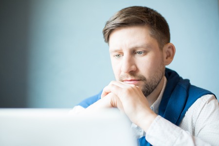 Thoughtful man near looking at laptopの写真素材