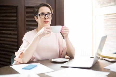 Elegant woman drinking near laptopの写真素材
