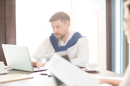 Man working on laptop near colleague