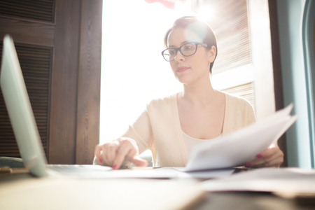 Focused woman working with documents and laptopの写真素材