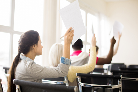 Multiracial group of people raising hands with papers on trainingの写真素材