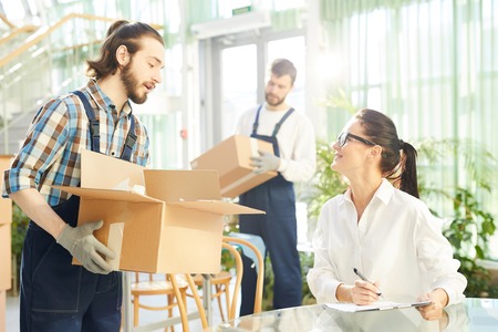 Positive businesswoman giving tasks to moversの写真素材