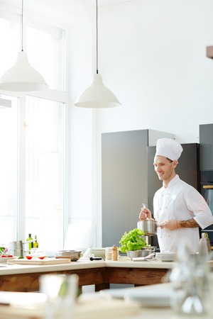 Positive chef cooking at modern kitchenの写真素材