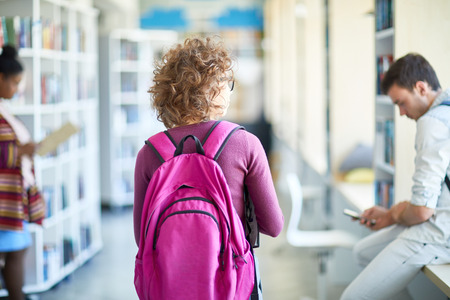 Student girl walking over library corridor