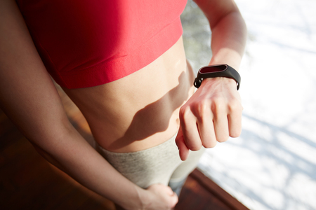 Anonymous sportswoman looking at fitness trackerの写真素材