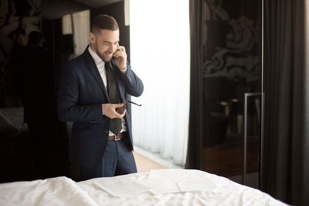 Businessman in hotel room speaking on phoneの写真素材