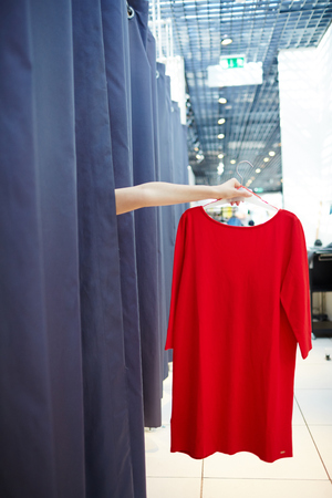 Crop hand holding dress in fitting roomの写真素材