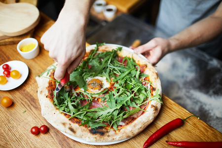 Cutting pizza before servingの写真素材
