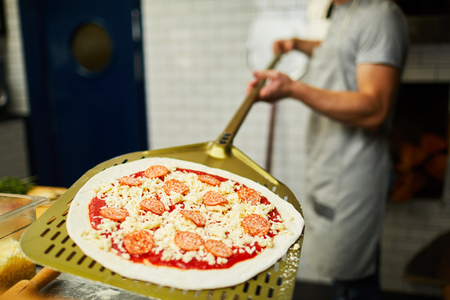 Putting pizza into ovenの写真素材