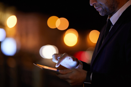 Elegant businessman using tablet for searching online information or reading news in the netの写真素材