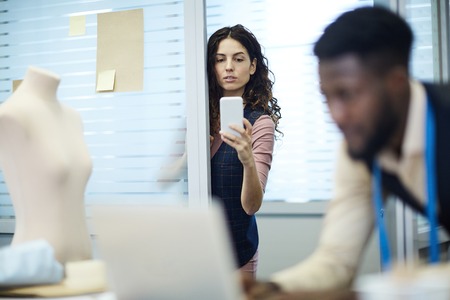 Woman photographing clothing designer at workの写真素材