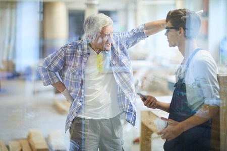 Furious carpenter foreman yelling at lazy workerの写真素材