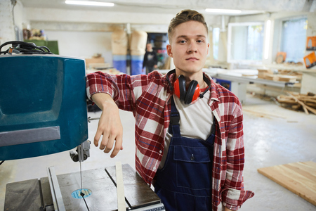 Serious handsome carpenter at drilling machineの写真素材