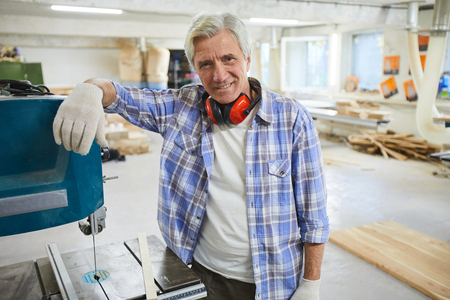 Smiling carpenter leaning on drilling machineの写真素材