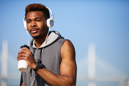 Pensive sporty guy refreshing after training