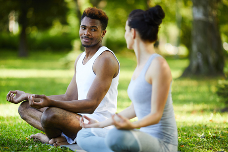 Content interracial couple talking during outdoor yoga practiceの写真素材