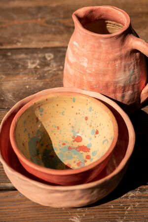 Set of new earthenware consisting of two painted bowls and jug on wooden table ready to use
