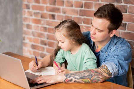 Daughter assisting father with workの写真素材