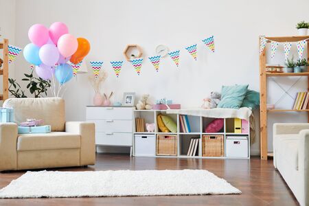 Bunch of colorful balloons and stack of giftboxes on armchair in the living-roomの写真素材