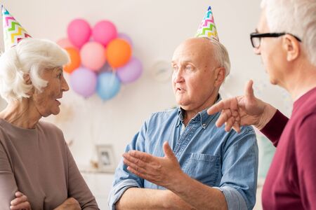 Group of senior men and woman talking at birthday partyの写真素材