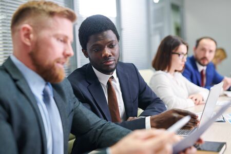 Young African broker looking at financial data