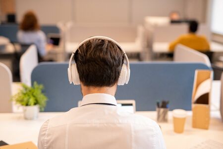 Rear view of office employee in wireless headphonesの写真素材