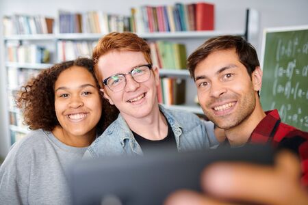 Cheerful college friends looking in camera while making selfie