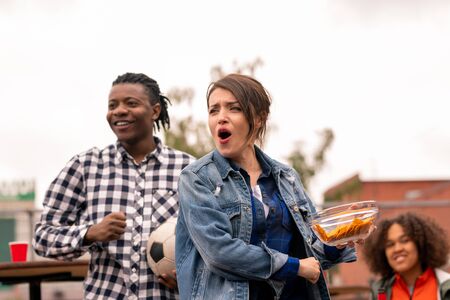 Young excited friends or dates with snack cheering for their football team