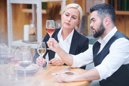 Serious and attentive sommeliers evaluating color of wine sample