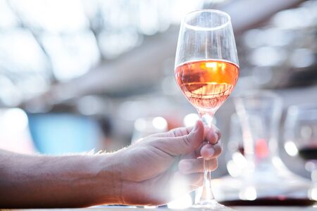 Human hand holding bokal of white wine or brandy while going to drink itの写真素材