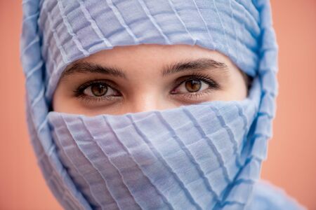 Beautiful eyes of young muslim woman with her face hidden behind blue hijab