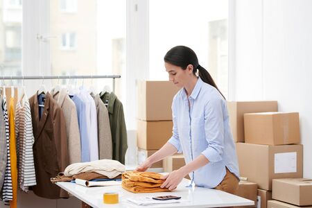 Young manager folding one of items of new seasonal casualwear collection