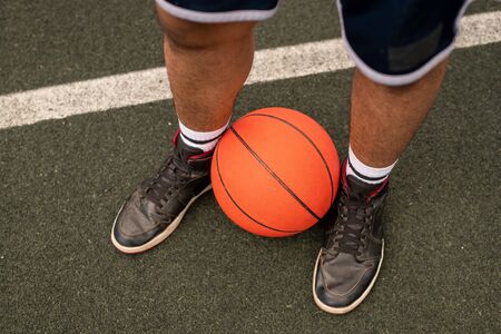 Ball by legs of young professional basketball playerの写真素材