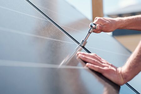 Hands of contemporary master with screw adjusting or installing solar panelsの写真素材