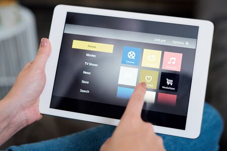 Young female touching heart icon on display while choosing something to watch