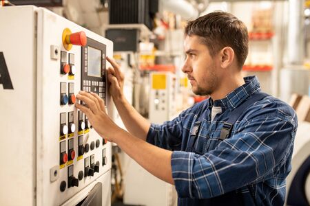 Young worker choosing parameters of raw thermoplastic material processing