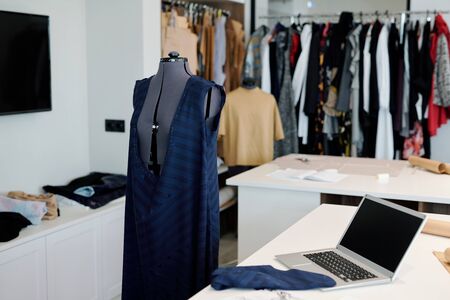 Workplace of contemporary seamstress or tailor with unfinished clothing item on mannequin, laptop...
