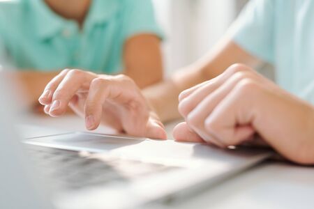 Hand of young woman or teenage girl over keypad of laptop during network