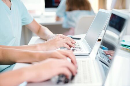Two contemporary students of school or college typing on laptop keypads