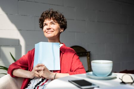 Pretty young woman with open book or notebook getting inspired on sunny dayの写真素材