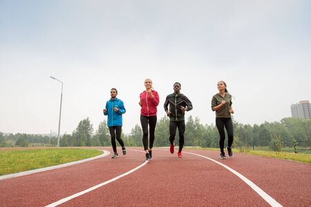 Four young male and female athletes in sportswear running marathonの写真素材