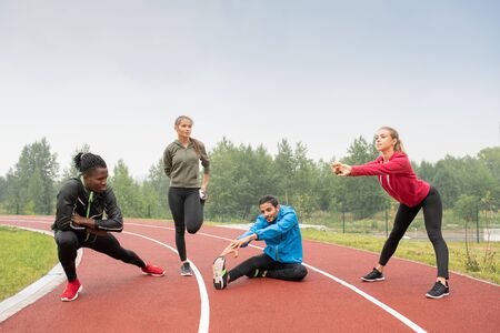 Young healthy intercultural men and women in sportswear doing physical exercisesの写真素材