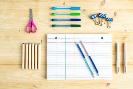 Top view of paper, some clips, pencils, highlighters, pens and scissors