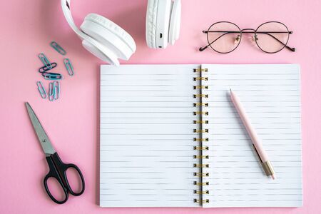 Open copybook with pen, eyeglasses, scissors, clips and headphonesの写真素材