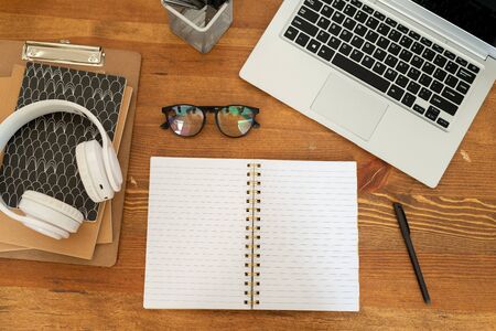 Overview of open notebook with blank pages surrounded by other supplies