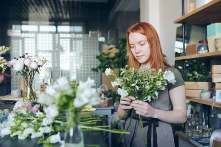 Young flower storekeeper making tender bouquetの写真素材