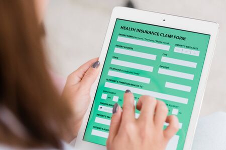 Hands of young woman holding touchpad with health insurance form