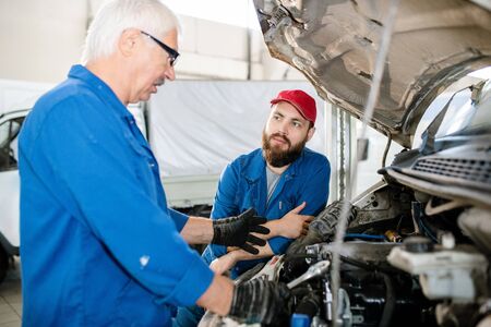 Young bearded worker of technical service looking at his mature colleague