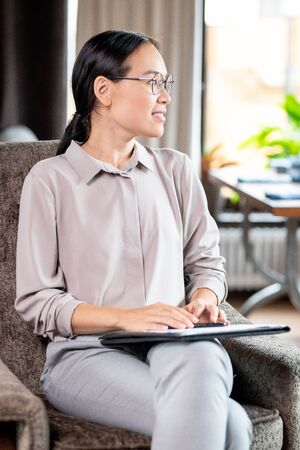 Young elegant female employee sitting in soft comfortable armchairの写真素材