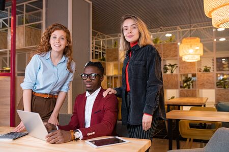 Small group of young successful intercultural employees looking at you